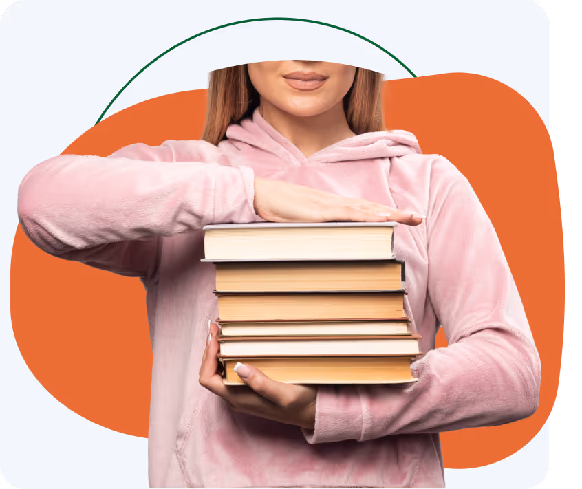 Person in a pink hoodie holding a stack of books