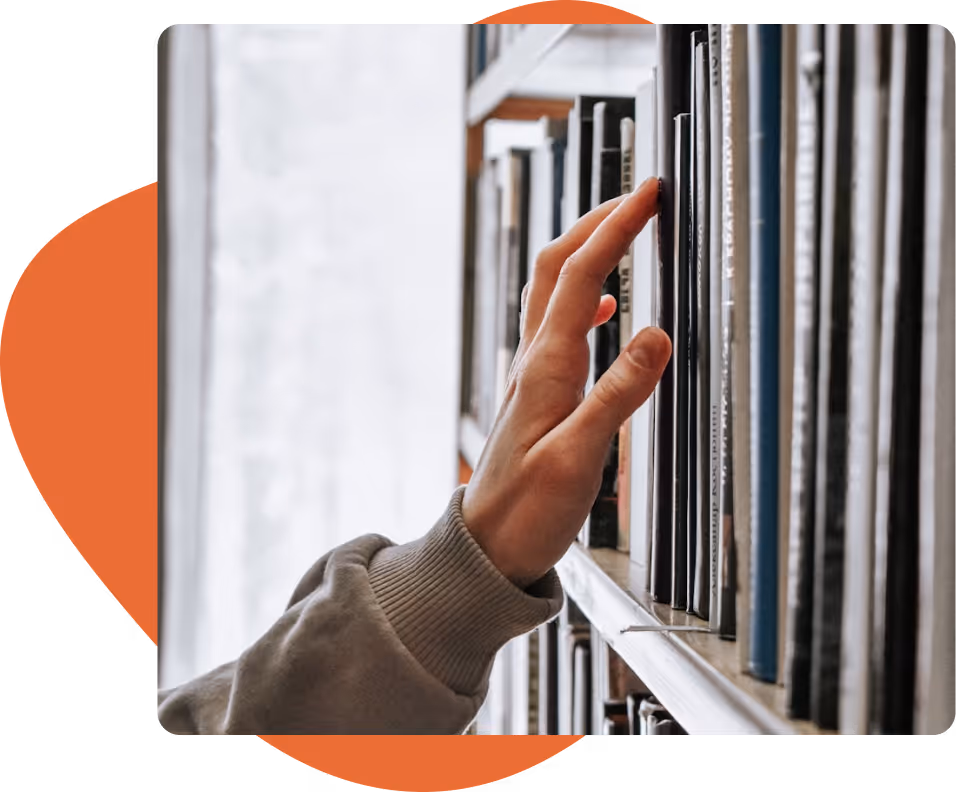 A hand reaching for a book on a shelf